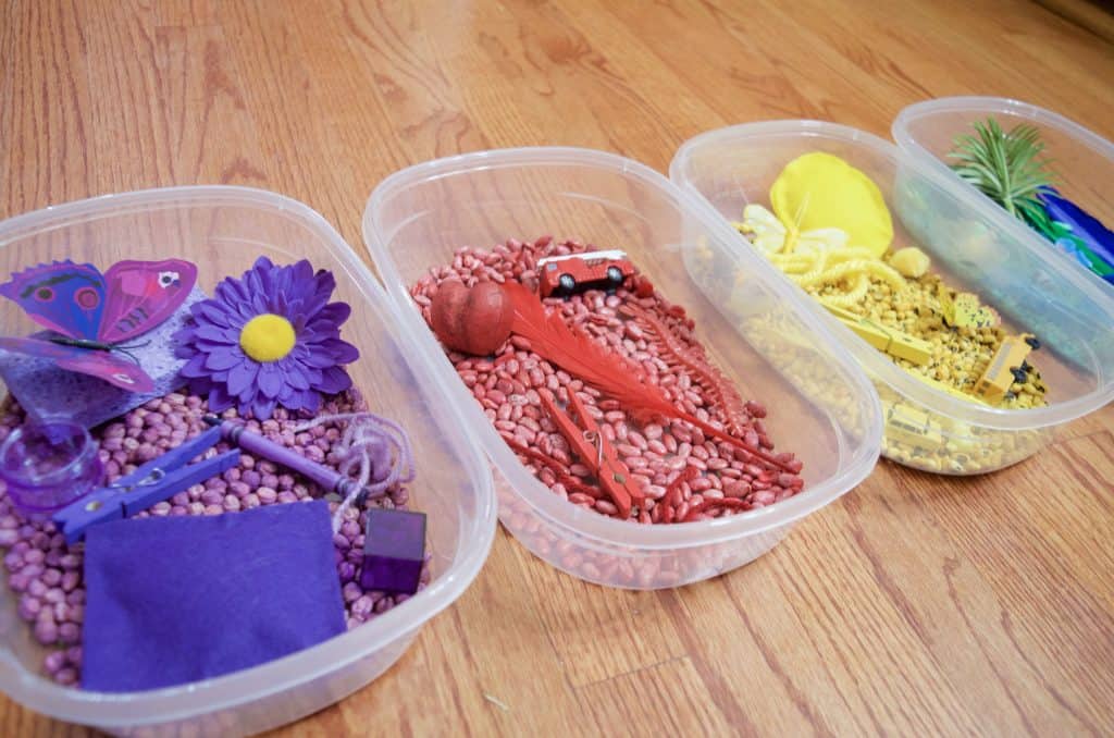 row of colored sensory bins for play